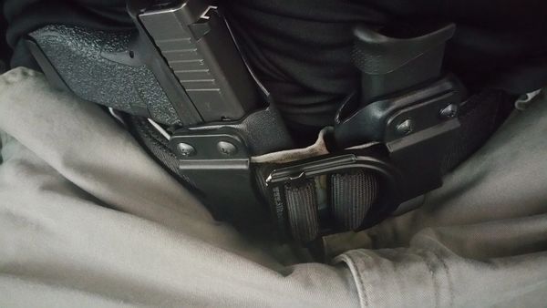 A gun is strapped to the side of someone's pants.