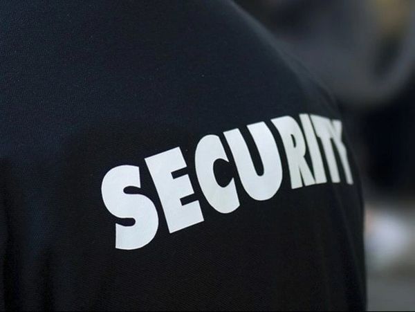 A security officer is wearing his uniform and has the word " security " on it.