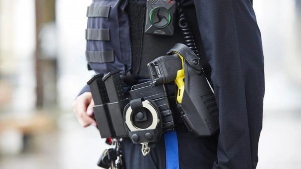 A police officer wearing a body camera and holster.