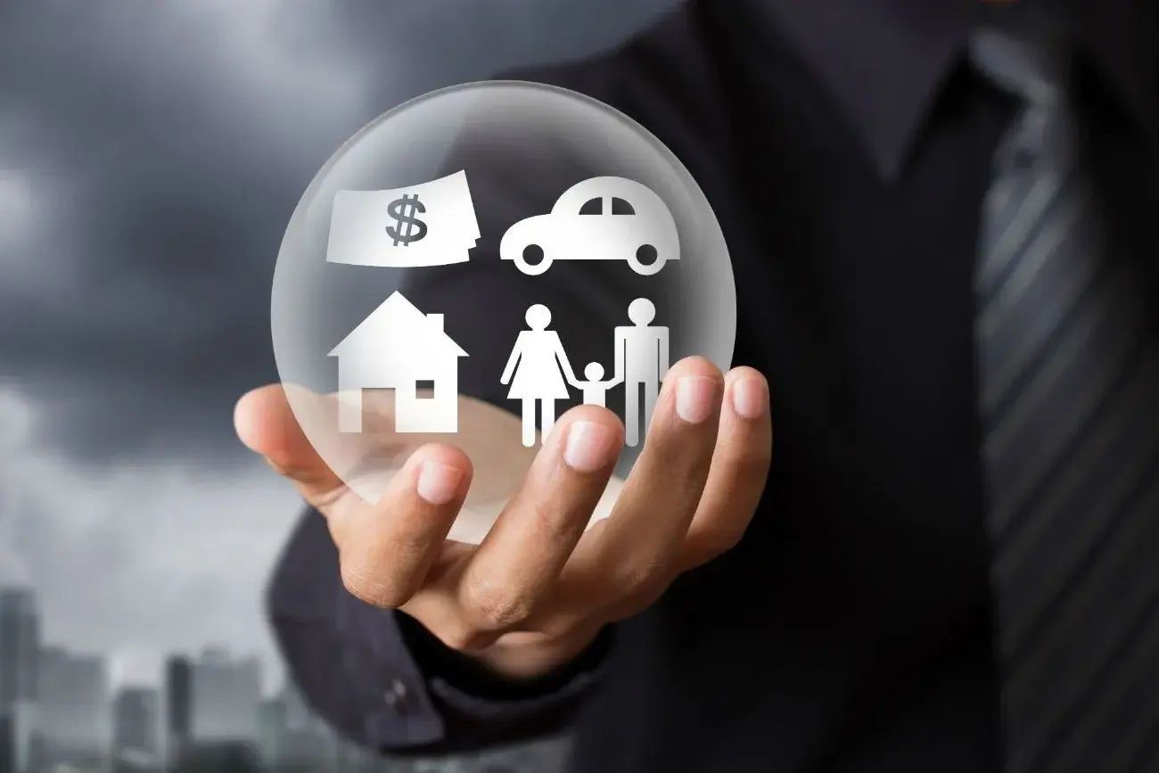 A person holding a glass ball with pictures of a family, car, house, and money inside.
